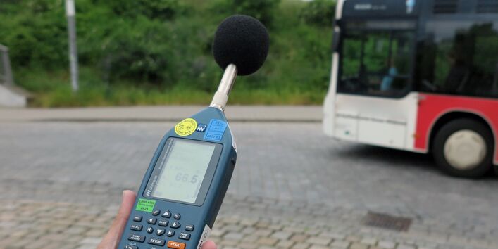 Ein vorbeifahrender Omnibus wird mittels Handschallpegelmessgerät akustisch gemessen