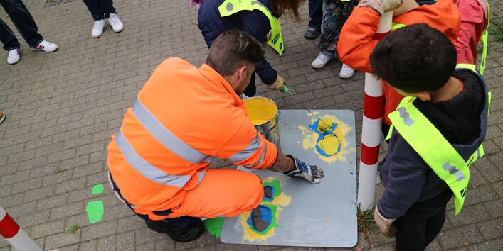 Schülerinnen und Schüler malen Füße unter Anleitung in den Straßenraum