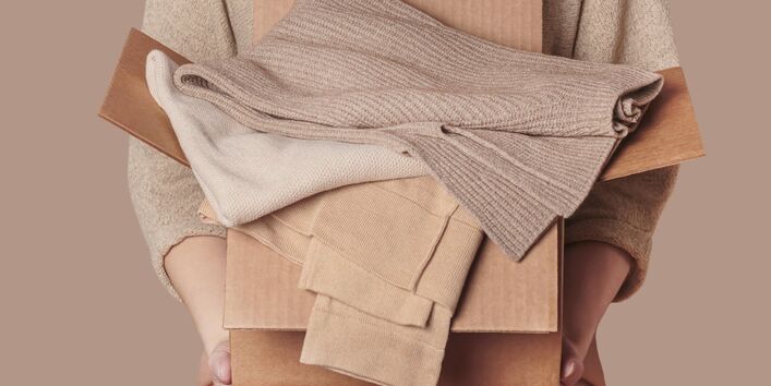 Ein Mensch liegt unter einem Haufen von Kleidern