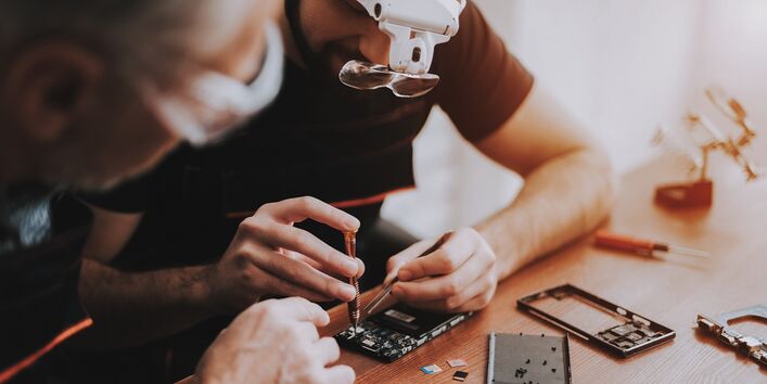 Zwei Männer haben ein Elektrogerät aufgeschraubt, um es zu reparieren