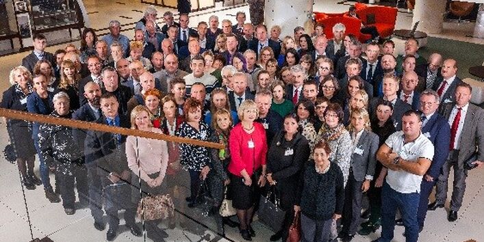 Blick von einer Treppe in eine Empfangshalle, dort stehen ca. 60 Personen nebeneinander mit Blick zur Kamera.