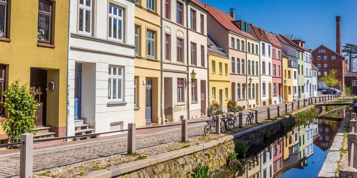 Das Bild zeigt innerstädtischen Gebäudebestand und abgestellte Fahrräder entlang eines Gewässers.