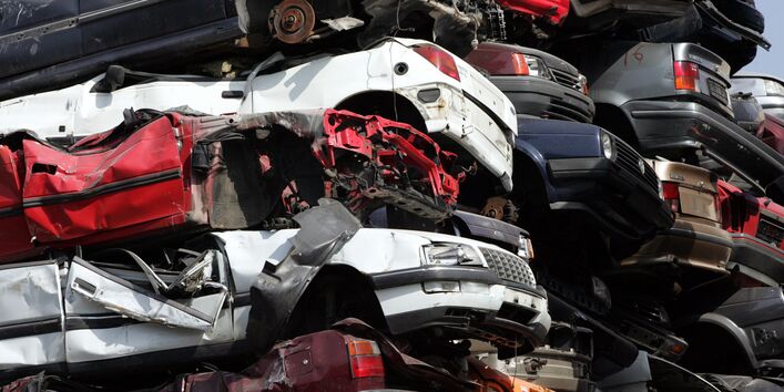 verschrottete Altautos mit demontierten Reifen auf einen Haufen getürmt
