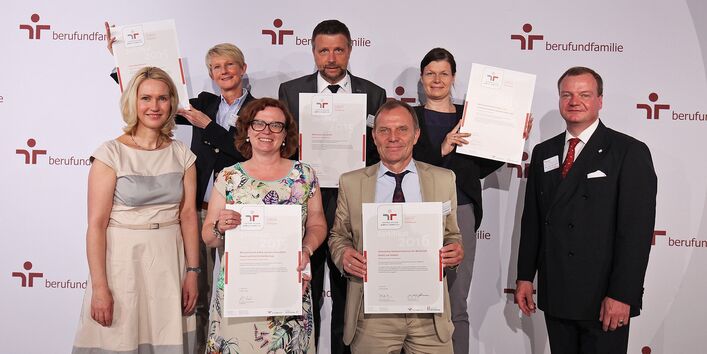 Gruppenfoto, die Personen halten das Zertifikat "Audit Beruf und Familie" 2015 in die Kamera