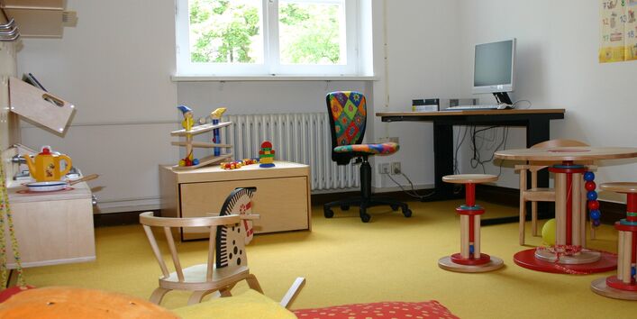 Zimmer mit Kinderbett, Spielzeug und einem Schreibtisch mit Computer für Erwachsene