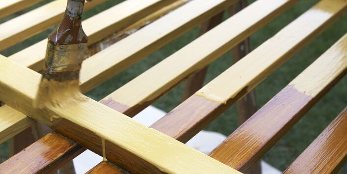 ein Holzzaun wird mit einem Pinsel gestrichen