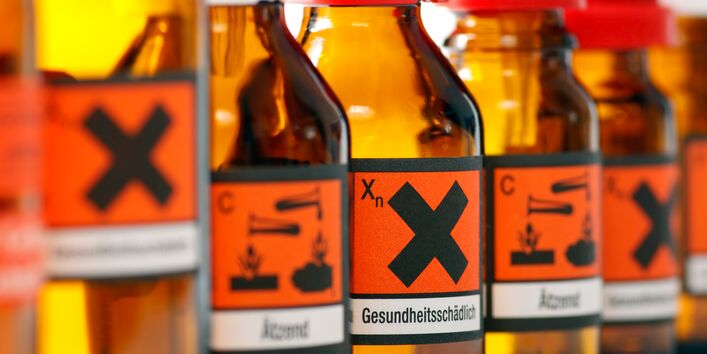 Glasfläschchen mit Warnhinweisen wie "ätzend" und "gesundheitsschädlich".
