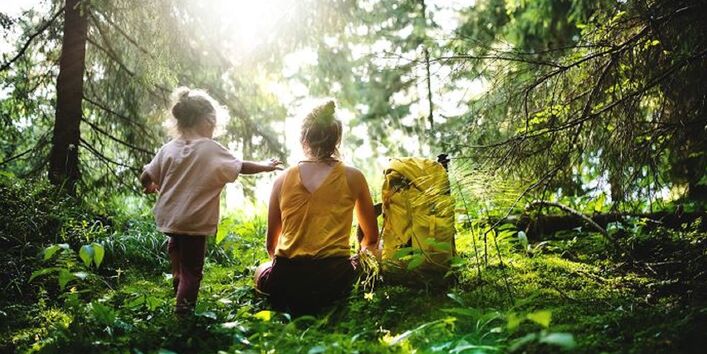 Frau mit Kind sitzend im Wald.