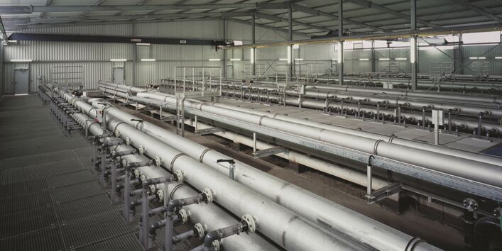 in einer Leichtbauhalle mit einem Boden aus Metallgittern steht eine große Anlage aus einem Rohrsystem