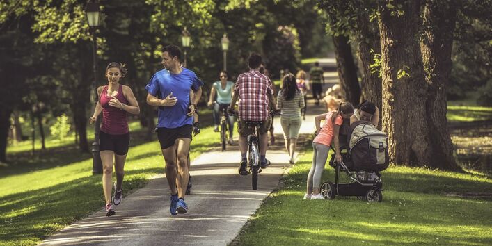Menschen in einem Stadtpark, die joggen oder spazieren gehen