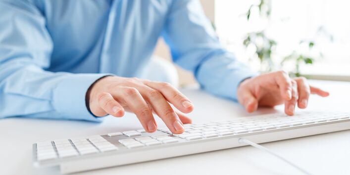 Mann tippt auf einer Computertatstatur