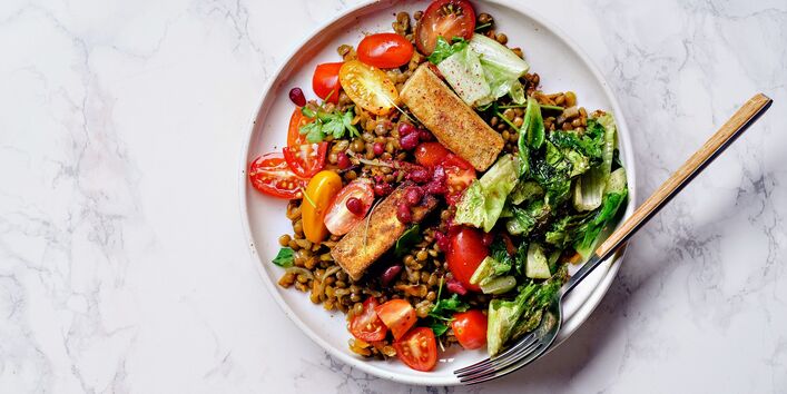 appetitlich angerichteter Teller mit Mittagessen aus Linsen, Gemüse und Salat