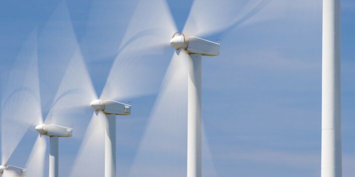 Windkraftanlagen drehen sich vor blauem Himmel