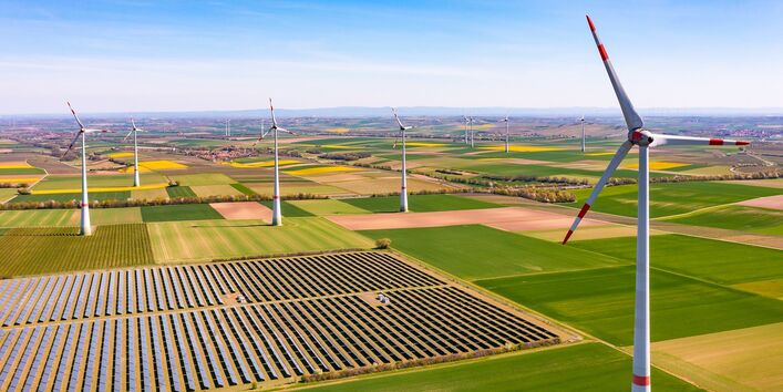 Wind turbines between agricultural land and a solar park