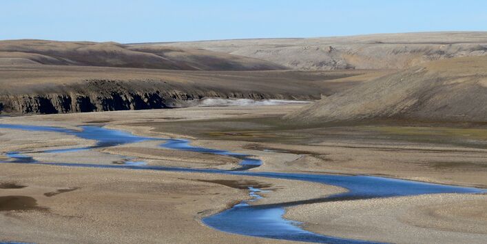 Ein Fluss schlängelt sich durch die karge arktische Landschaft.