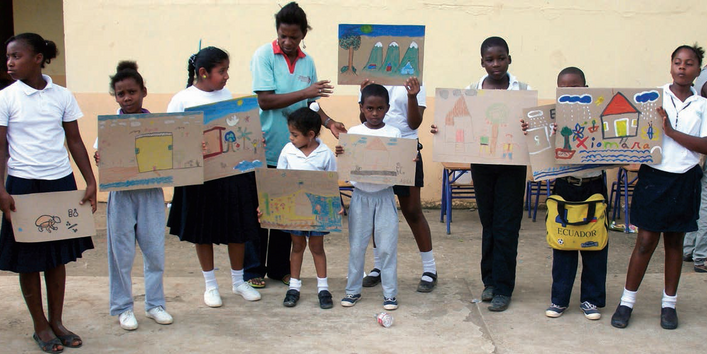 Kinder aus Ecuador zeigen in ihrem Klassenraum selbstgemalte Bilder.