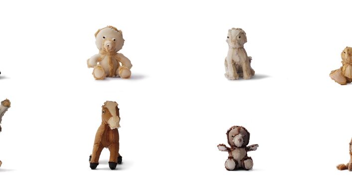 Kleine ganz unterschiedliche Secondhand-Kuscheltiere sitzen in einer Reihe