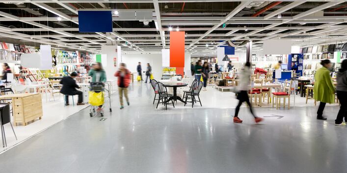 Ein Kaufhaus: Im verschwommenen Hintergrund kaufen mehrere Personen verschiedenene Produkte ein.