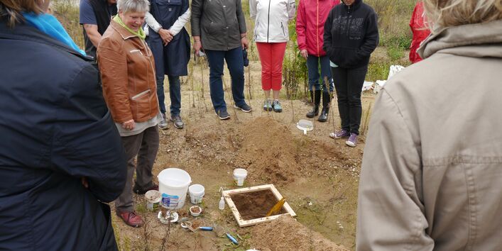Menschen stehen um ein Bodenfenster herum