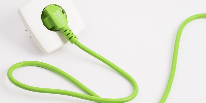 grünes Kabel mit Stecker in der Steckdose