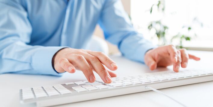 Mann tippt auf einer Computertatstatur