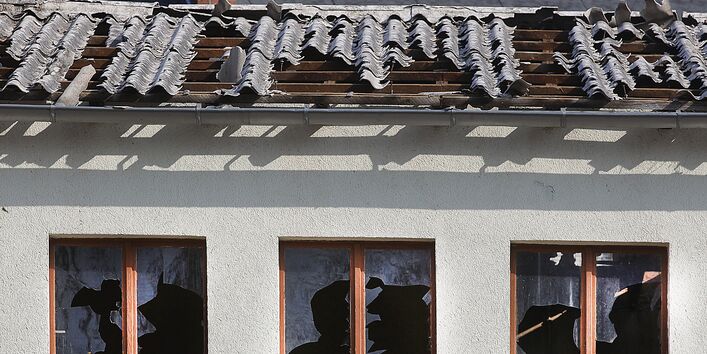 Gebäude mit zerbrochenen Fensterscheiben und teilweise abgedecktem Dach.