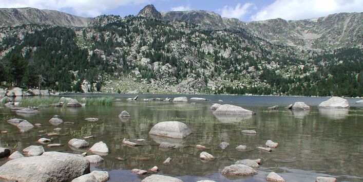 Ein See umgeben von Bergen mit klarem Wasser