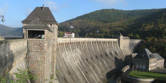 Blick von der Seite auf eine große Talsperre, die aussieht wie eine riesige Mauer