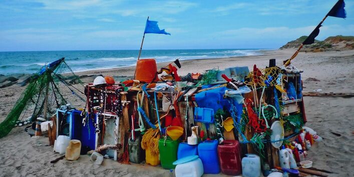 Ein Schiffskutter behängt mit bunten Plastikkanistern und -flaschen am Strand