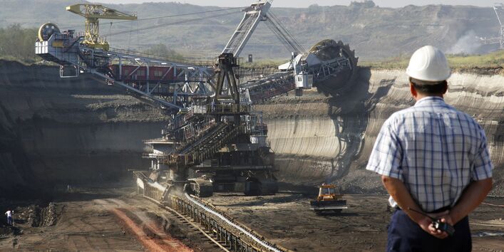 Ein Mann mit Bauhelm schaut auf einen Tagebau.