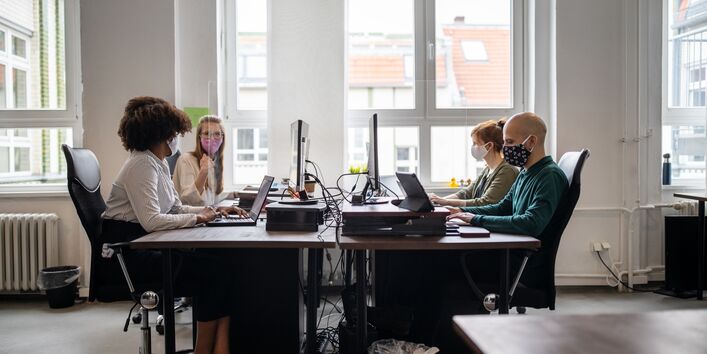 Eine Frau trägt einen Mundschutz und guckt aus dem Fenster