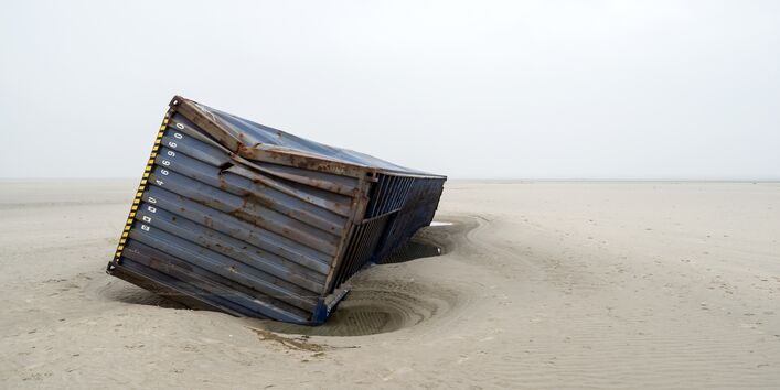 Ein havarierter Schiffscontainer liegt an einem Sandstrand.