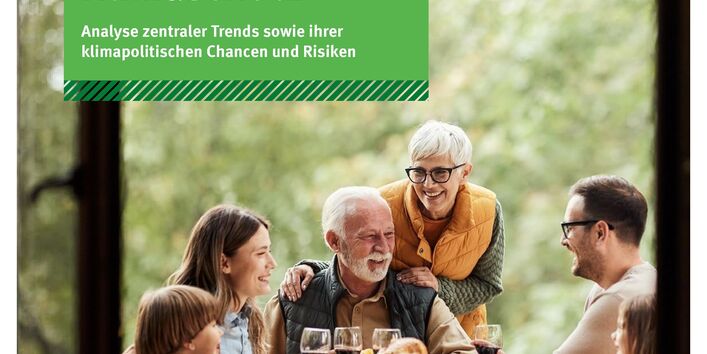 Menschen sitzen um einen gedeckten Tisch im Freien