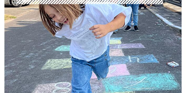 Ein Kind springt auf einer mit Kreide bemalten Straße herum