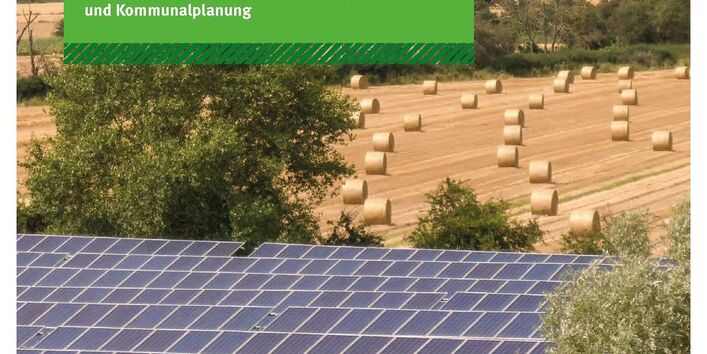 Solaranlagen auf einem Feld, dahinter abgeerntetes Feld und am Horizot Windräder