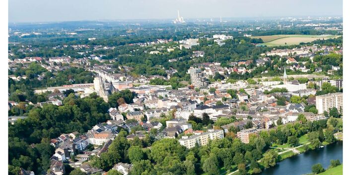 Stadt von oben, blauer Fluss im Vordergrund
