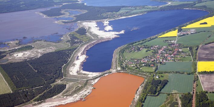 Luftbild einer Landschaft mit Tagebausee