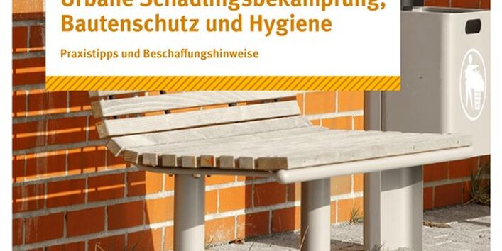 Eine Sitzbank und ein Mülleimer vor einer Backsteinmauer