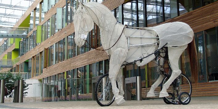 ein großes Pferd, gefertigt aus einem Gestell mit Papier bespannt, mit eingebauten Rädern & Fahrrad-Vorrsichtung