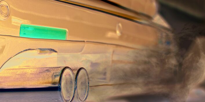 Das Bild zeigt den Auspuff eines Autos, aus dem Abgase herausströmen.