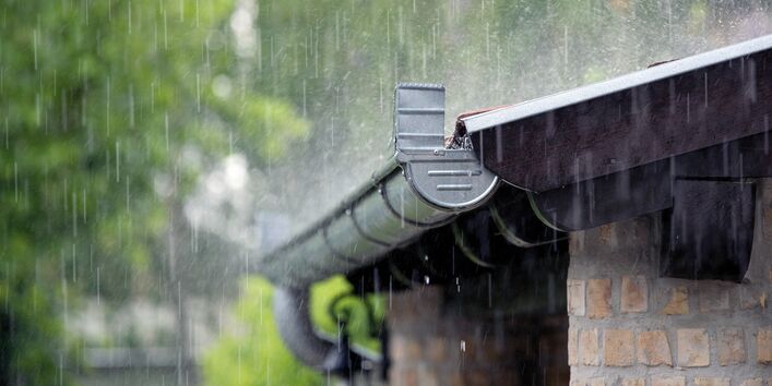 Das Bild zeigt die Regenrinne eines Hauses as Klinkermauerwerk. Es regnet stark.