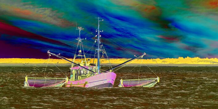 Das Bild zeigt einen Krabbenkutter auf der Nordsee. An der Seite des Schiffs hängt die Baumkurre. Im Hintergrund ist die Küste mit einem Leuchtturm zu erkennen.