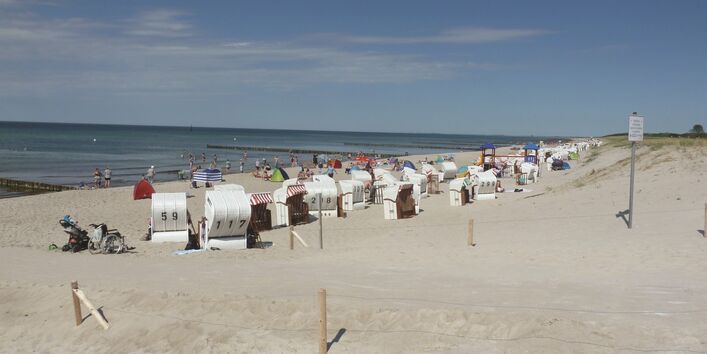 The picture shows a Baltic Sea beach with numerous beach chairs and the sea in bright weather.