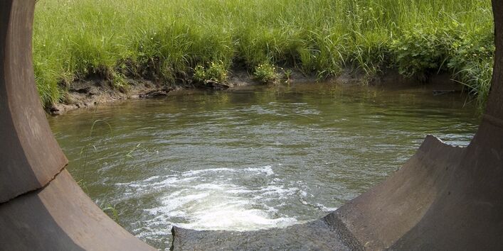 Auf dem Bild ist ein in ein Gewässer entwässernder Abwasserkanal zu sehen