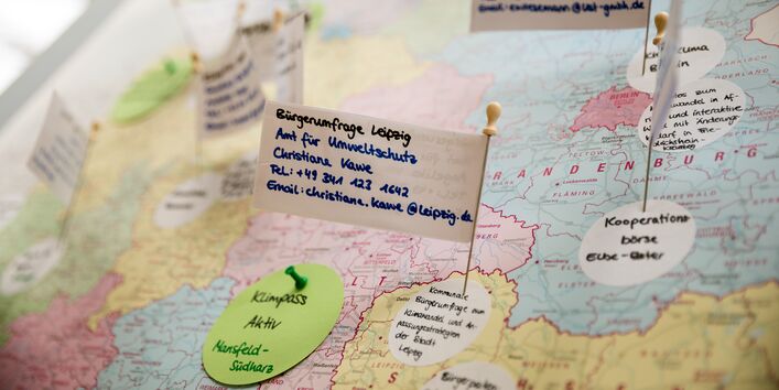 Auf kleinen Fahnen und kleine runde Moderationskreisen stehen Informationen zu Beteiligung. Diese markieren den Ort auf einer Deutschlandkarte.