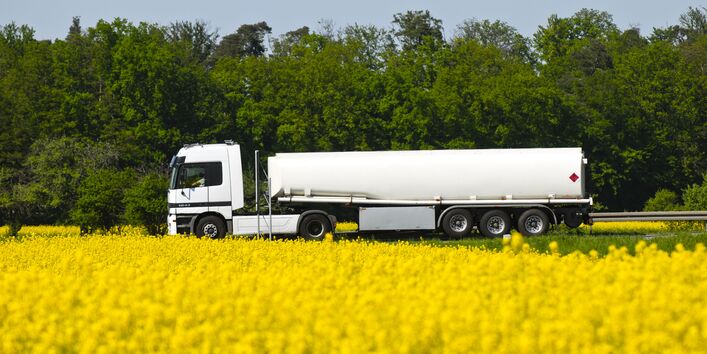 Weißer Tankwagen auf einem Rapsfeld