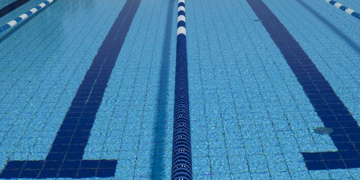 Das Wasserbecken eines Schwimmbades, wo die Bahnen durch schwimmende Abgrenzungen voneinander abgetrennt sind. Nahaufnahme