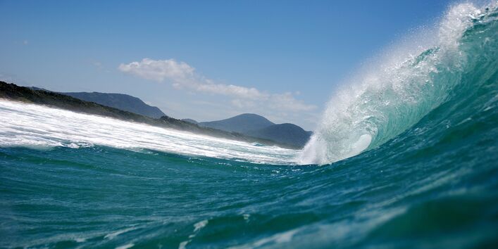 Nahaufnahme einer großen Welle, die kurz davor ist in die Brandung zu stürzen