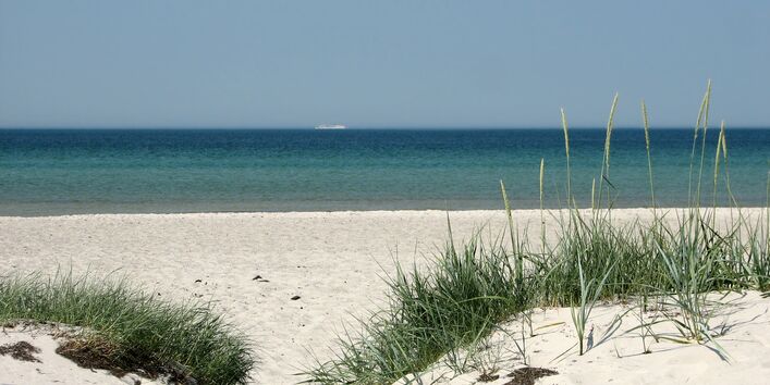 Im Vordergrund eine weiße Sanddüne und im Hintergrund das türkisblaue Meer