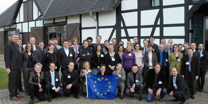 Eine Menschengruppe steht vor einem Fachwerkhaus